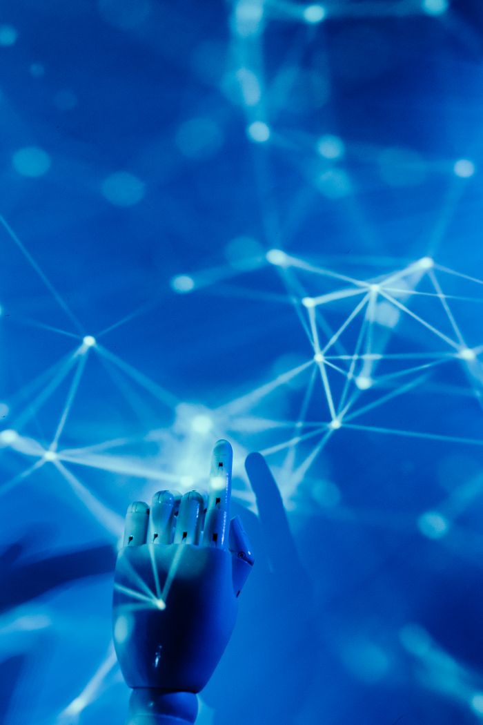 Best Free AI Tools for Small Business Owners in 2026 Futuristic robotic hand touching a digital network on a blue background.